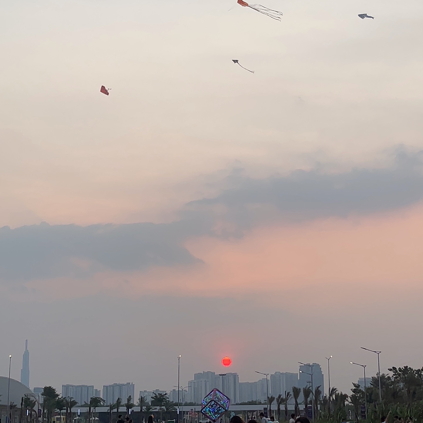 Hoàng hôn ở bãi thả diều The Global City, diều bay trên nền trời hồng, xa xa là tòa Landmark 81 và các khu căn hộ Thủ Đức